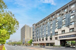 Ein mehrstöckiges Hotel mit moderner Architektur, inklusive Balkonen und einem Ladenbereich im Erdgeschoss.