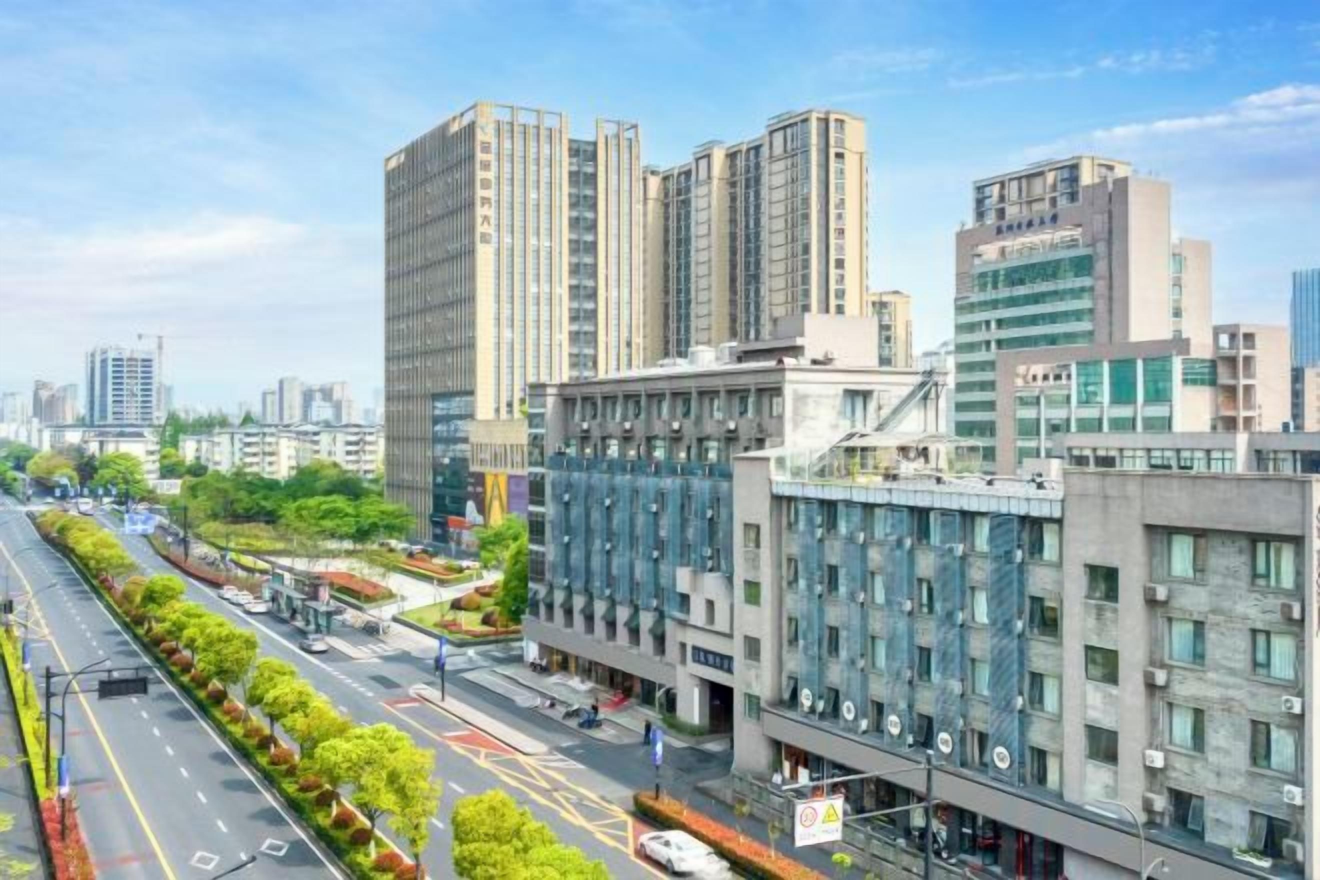 A cityscape with modern buildings, a wide road, and a clear sky.