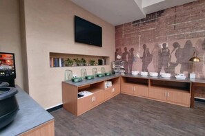 A modern kitchen with wooden cabinets, a flat-screen TV, and decorative items on shelves. - Hanxiang Hotel (Hangzhou Wenyi West Road Branch University of Finance and Economics) (Hangzhou)