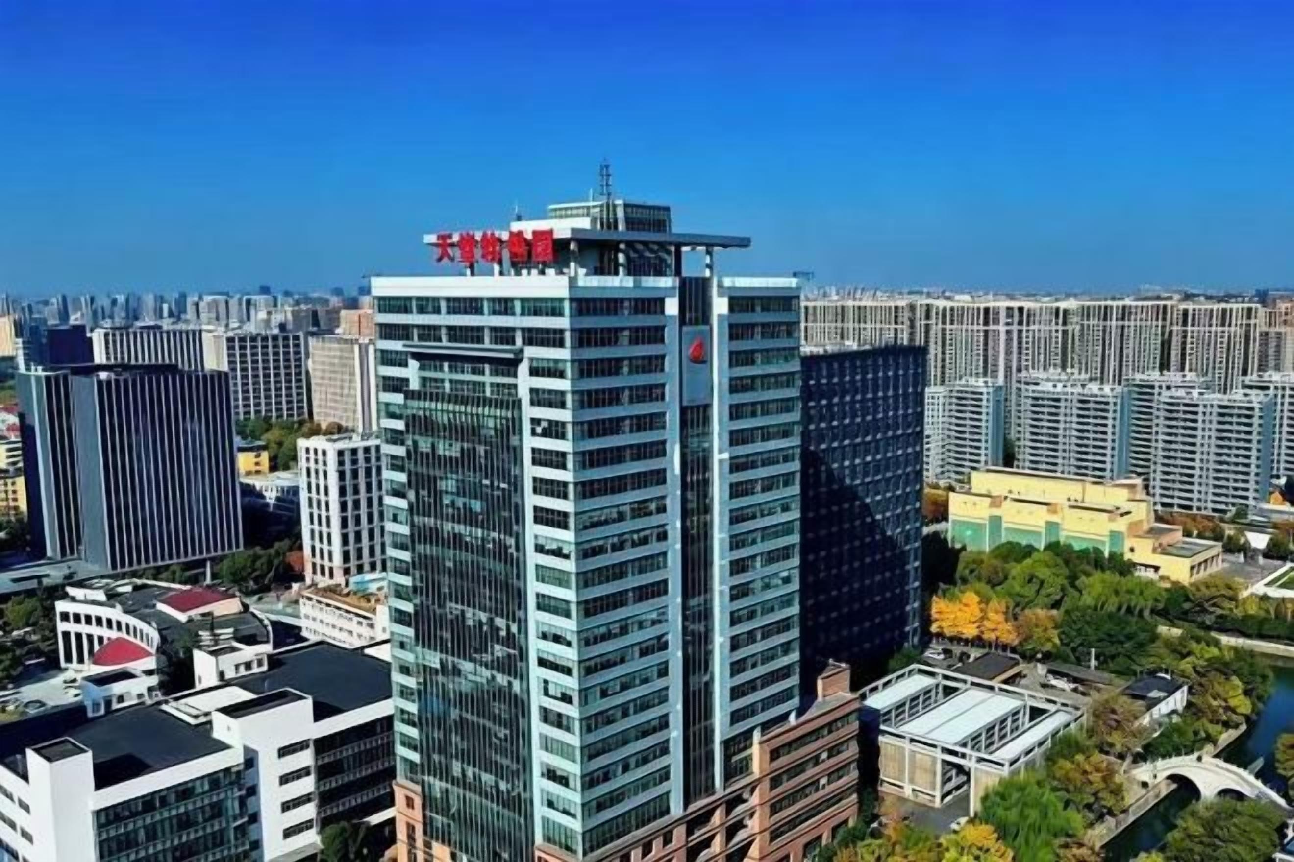 A high-rise building with a modern glass facade, surrounded by other high-rise buildings, indicating a dense urban environment.