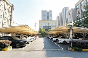 A parking lot with cars and covered parking structures. - Hanxiang Hotel (Hangzhou Wenyi West Road Branch University of Finance and Economics) (Hangzhou)
