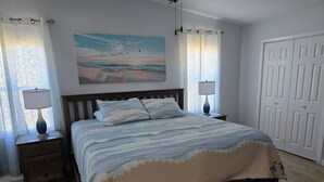 Een slaapkamer met een bed, twee nachtkastjes, een schilderij en een deur.