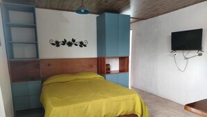 Ein Schlafzimmer mit Bett, einem an der Wand montierten Fernseher und einem Kleiderschrank.