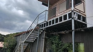 Ein zweistöckiges Gebäude mit einem Balkon und einer Treppe, die zum oberen Stock führt.