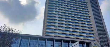 Un edificio de varios pisos con un diseño arquitectónico moderno, que destaca por un elemento vertical prominente en el lado derecho.