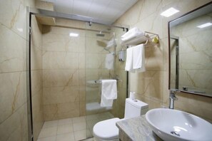 A bathroom with a glass-enclosed shower, a toilet, and a sink.