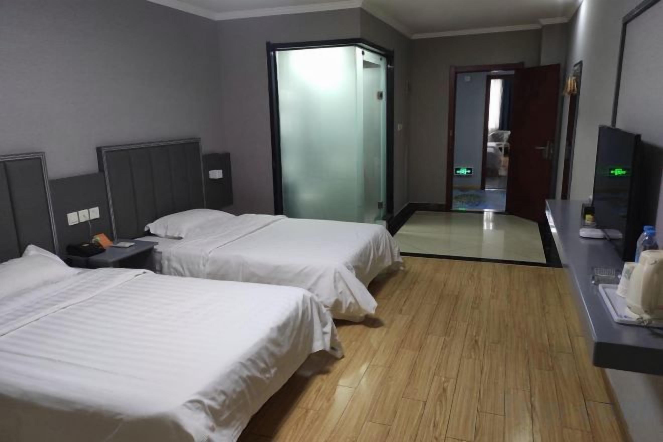 A hotel room with two beds, a desk with a computer, and a mirror.