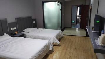 A hotel room with two beds, a desk with a computer, and a mirror.