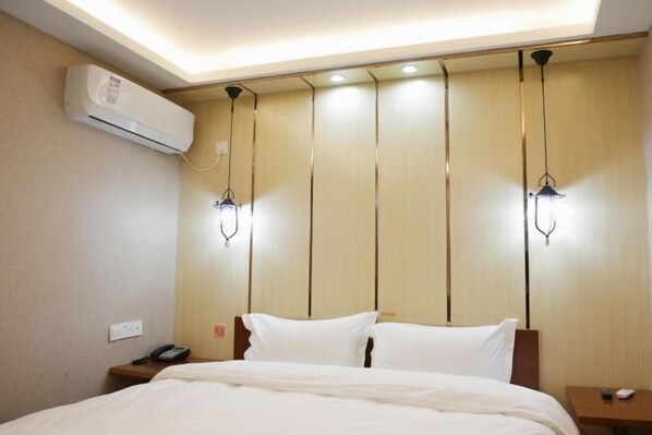 A hotel room with a bed, bedside tables, an air conditioning unit, and pendant lights.