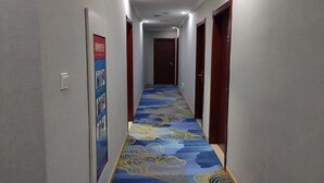 A hallway with a patterned carpet, doors on both sides, and a poster on the left wall. - 7Days Inn Chain Hotel (Xuancheng High-Speed Railway Station) (Xuancheng)