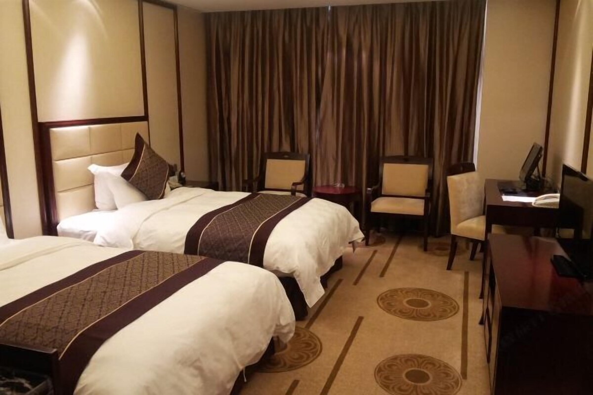 Ein Hotelzimmer mit zwei Betten, einem Schreibtisch und einem Stuhl.