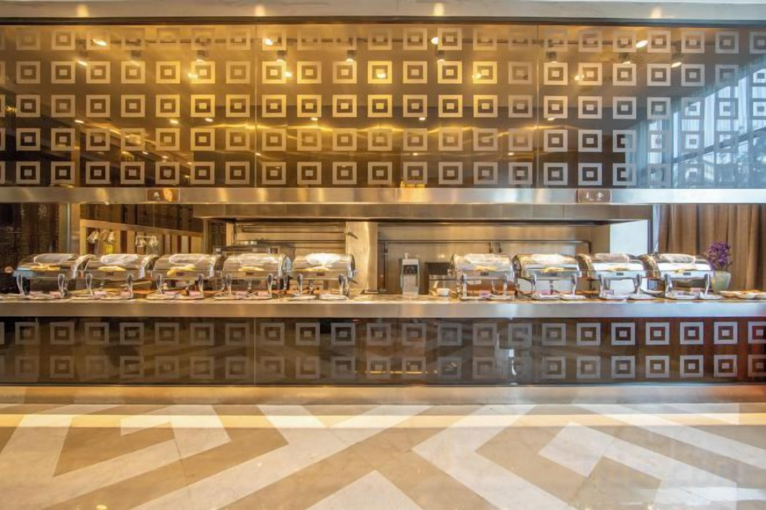 A buffet area with a patterned wall and a counter with food containers.