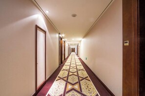A hotel hallway with a patterned carpet, doors on both sides, and a light fixture on the ceiling. - Chang'an Baiyun Hotel (Beijing)