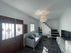 Relax in a spacious living area with a comfortable sofa, TV, and shelving unit.