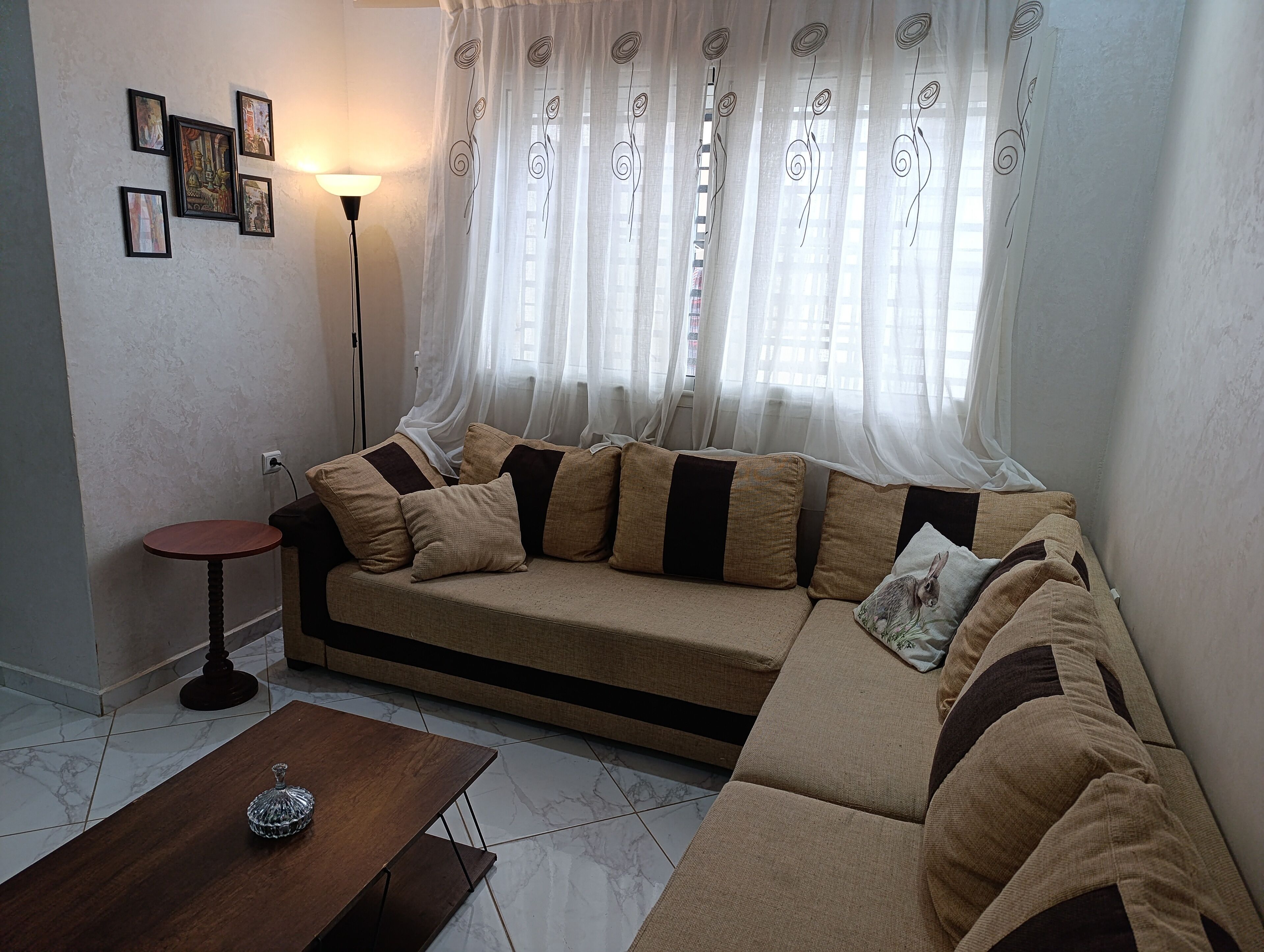 A living room with a sofa, a small table, and a floor lamp.