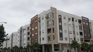 Ein mehrgeschossiges Wohngebäude mit moderner Architektur, das Balkone und verschiedene Fensterformen aufweist.