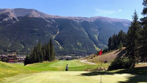 A golf course with a flag, a person in a blue shirt, and a mountainous backdrop. - Amazing Copper Mountain Views! Steps to Lifts! (Frisco)