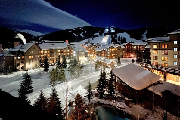 A snow-covered resort with multiple buildings, a ski lift, and a pool area.
