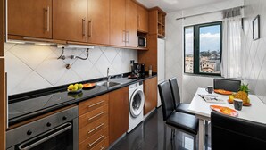 Eine moderne Küche mit Holzausstattung, einer integrierten Waschmaschine und einem Essbereich mit Blick auf die Stadt.
