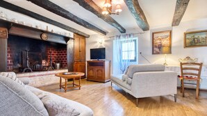 Una sala de estar acogedora con chimenea, vigas de madera, televisor y asientos cómodos.