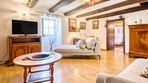 Una sala de estar con televisor, muebles de madera, una mesa redonda y un sofá.