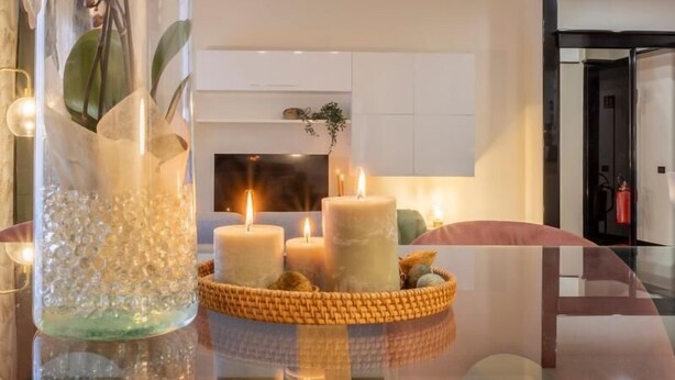 A modern living room with a glass coffee table, candles, and a vase with flowers. - Morgana Charming Apartment Close to Vatican (ROMA)