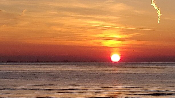 Un atardecer sobre una masa de agua tranquila con un horizonte despejado.