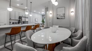Een moderne keuken met witte kasten, een roestvrijstalen koelkast en een centraal keukenblok met zitplaatsen.