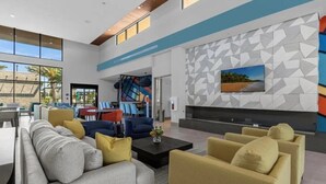 Een ruime lobby met een modern design, met een grote zithoek met sofa’s en fauteuils, een open haard en een abstract kunstwerk aan de muur.