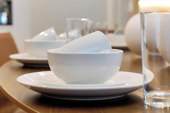 Un tazón de cerámica blanca sobre un plato blanco, con un vaso de agua al lado.