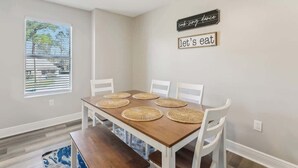 A dining area with a wooden table, white chairs, and woven placemats. - Beautiful Apartment (Slidell)