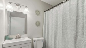 A bathroom with a white sink, mirror, and toilet. - Beautiful Apartment (Slidell)