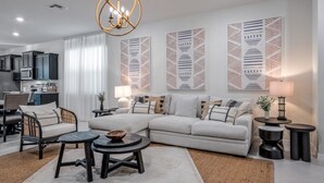 Un salon moderne avec un canapé d’angle, une table basse ronde et un coin repas avec des chaises.