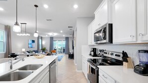 Una cocina moderna con armarios blancos, electrodomésticos de acero inoxidable y una isla central con pileta.