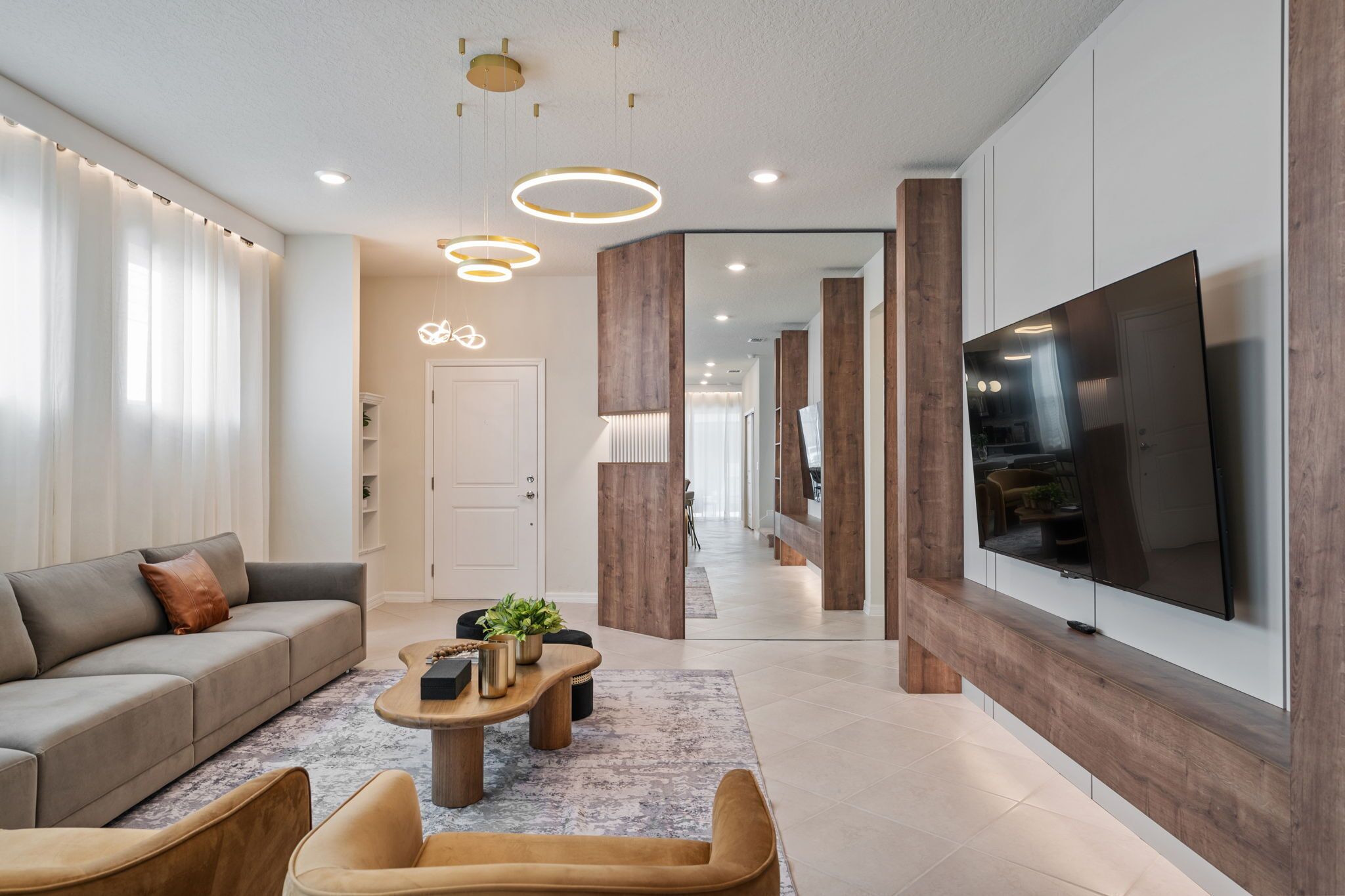Ein modernes Wohnzimmer mit einer Couch, einem Couchtisch und einem an der Wand montierten Fernseher.