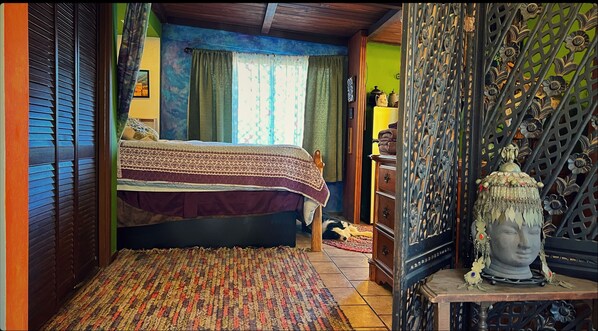 A bedroom with a bed, a wooden headboard, a patterned rug, a dresser, and a decorative metal gate. - Charming bungalow with an Amazing view of Sequoia National Park in Three Rivers. (Three Rivers)