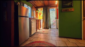 A kitchen with a refrigerator, stove, and cabinets. There is a window with curtains and a door leading outside. - Charming bungalow with an Amazing view of Sequoia National Park in Three Rivers. (Three Rivers)