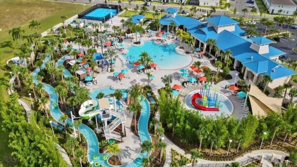 An aerial view of a resort with multiple swimming pools, water slides, and lounge areas surrounded by palm trees. - Luxe Retreat - Beautiful Modern 7 Bedrooms Home (Davenport)