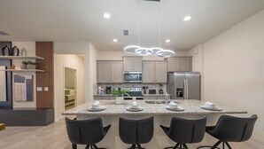 A modern kitchen with granite countertops, stainless steel appliances, and black bar stools. - Luxe Retreat - Beautiful Modern 7 Bedrooms Home (Davenport)