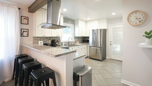 Una cocina moderna con una isla central, electrodomésticos de acero inoxidable y un reloj en la pared.