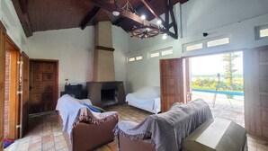 A rustic room with a fireplace, two sofas, and a balcony with a view. - Mini Pantanal Paulista with a paradisiacal view, a place to listen to the birds (Ibitiruna)