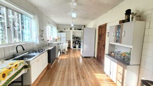 A kitchen with a wooden floor, white cabinets, a sink, and a stove. - Mini Pantanal Paulista with a paradisiacal view, a place to listen to the birds (Ibitiruna)