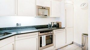 Una cocina moderna con armarios blancos, horno de acero inoxidable, microondas y un lavamanos.