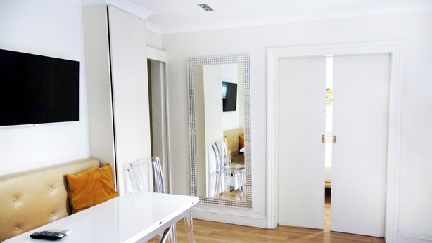 Una habitación de hotel moderna con un espejo grande, una mesa blanca y un sofá.