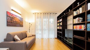 Un salon avec un canapé, une bibliothèque et un tableau accroché au mur.