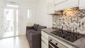A modern kitchen with a built-in stove, a sofa, and a patterned backsplash. - Termopili29 Cozy apartment in NoLo by Hospity (Milano)