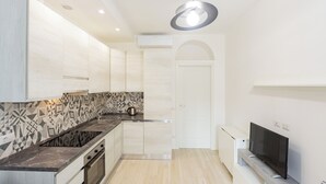 A modern kitchen with a built-in stove, a coffee machine, and a TV on a stand. - Termopili29 Cozy apartment in NoLo by Hospity (Milano)