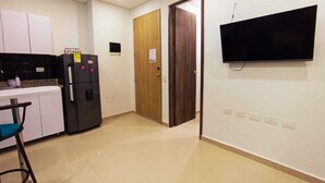 A kitchen with white cabinets, a black refrigerator, and a wooden door. - a una cuadra de la playa  (Santa Marta)