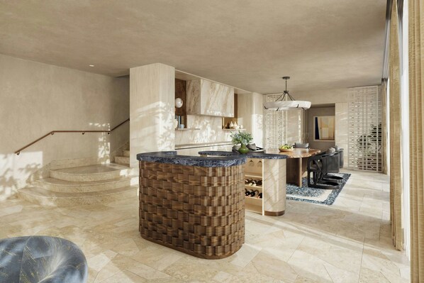 Una cocina amplia con una isla central, un comedor y una escalera que conduce a un nivel superior.