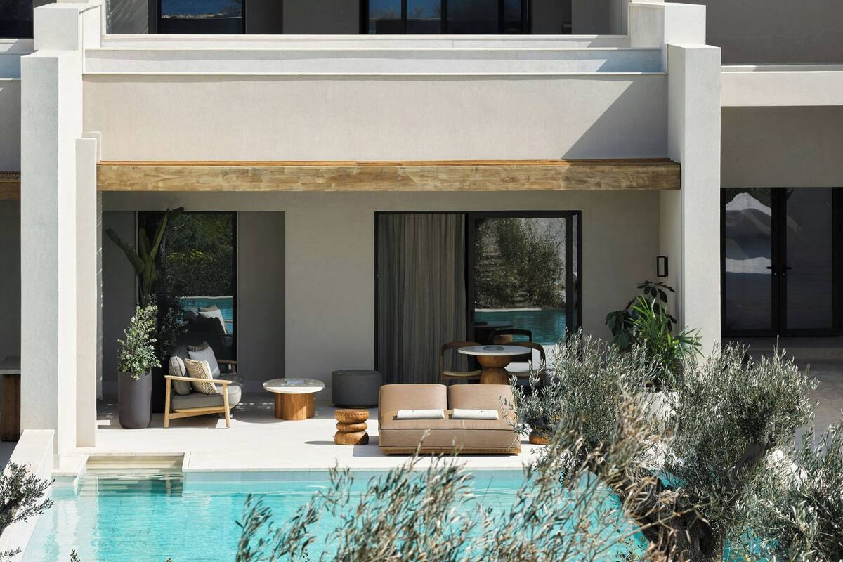 A modern outdoor living area with a pool, seating, and potted plants.